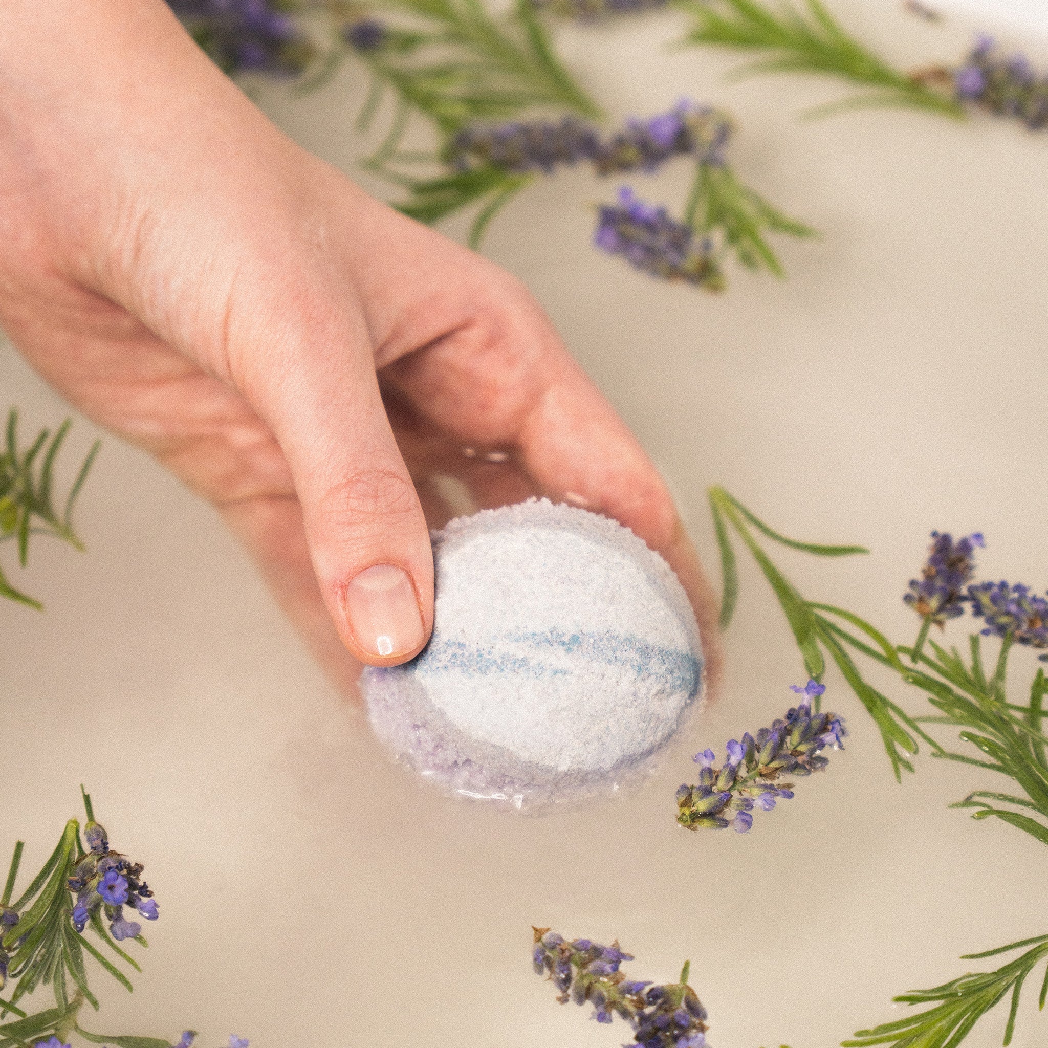 Hands holding Eir's 'Midnight Chill' bath bomb, ready to be immersed in water, for a relaxing bath experience.